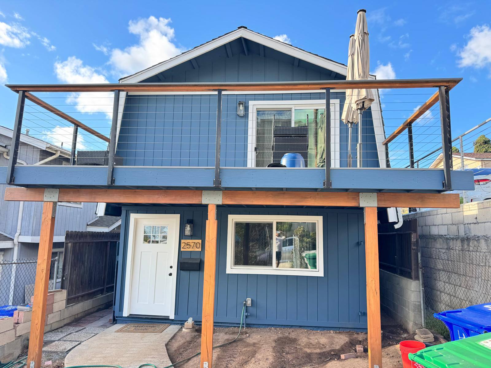 After: front of home with blue-painted deck and natural stained wood posts