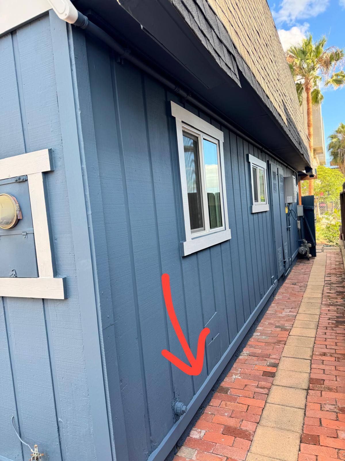 After exterior painting — red arrow showing where the wood trim was installed at base of siding